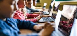 Nenos e nenas usando ordenadores portátiles.