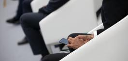 Home traxeado sentado usando un smartphone.