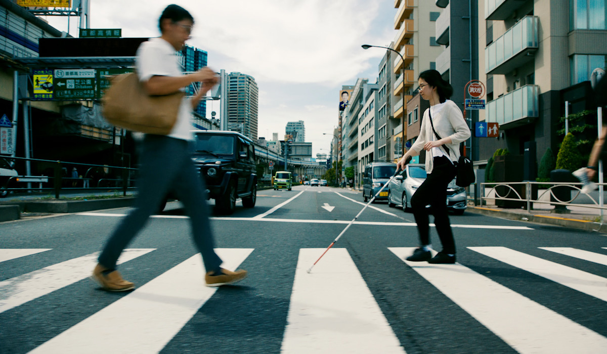 Persona con discapacidad visual cruzando por un paso de cebra.