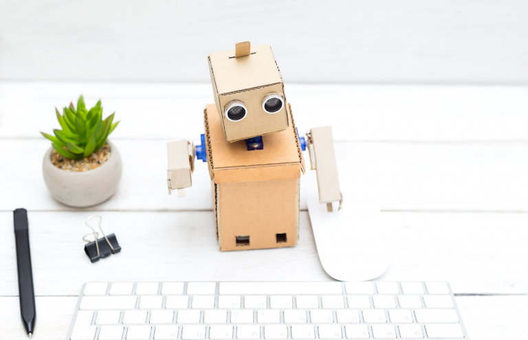 Robot de cartón a un lado de un teclado y un ratón.