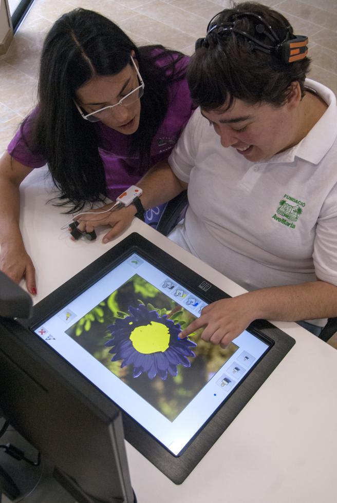 Laia Valls, con la integradora social Marta Muñoz, mientras realiza tareas de estimulación cognitiva en la plataforma Armoni (Carles Castro / GARRAF NEWS MEDIA).