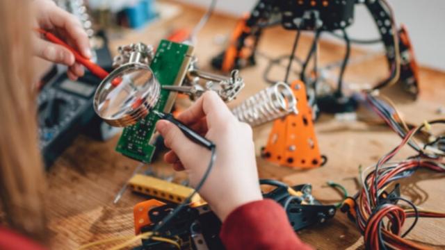 Persona joven comprobando una placa electrónica.