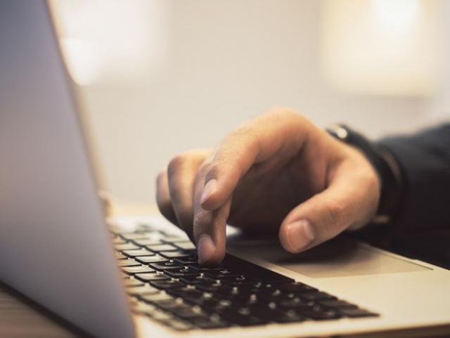 Mano tecleando sobre un portátil.