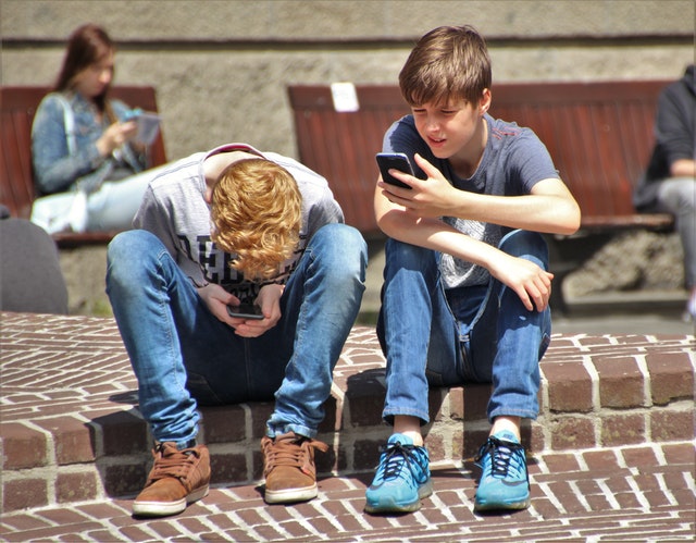 Dos chicos usando smartphones.
