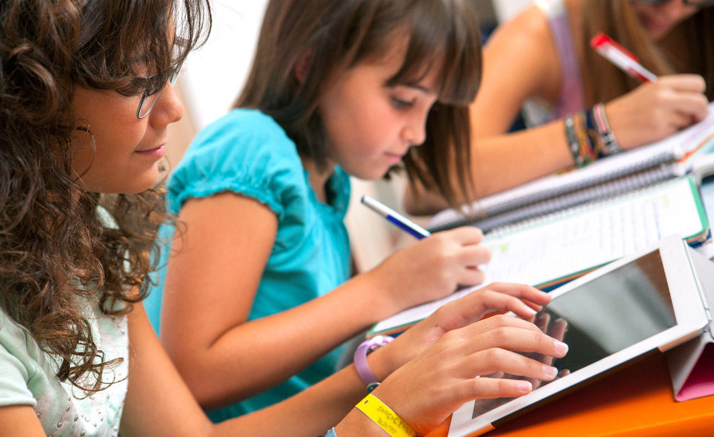 Unha nena con discapacidade auditiva segue a clase a través dunha tableta.