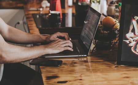 Mans tecleando nun portátil.