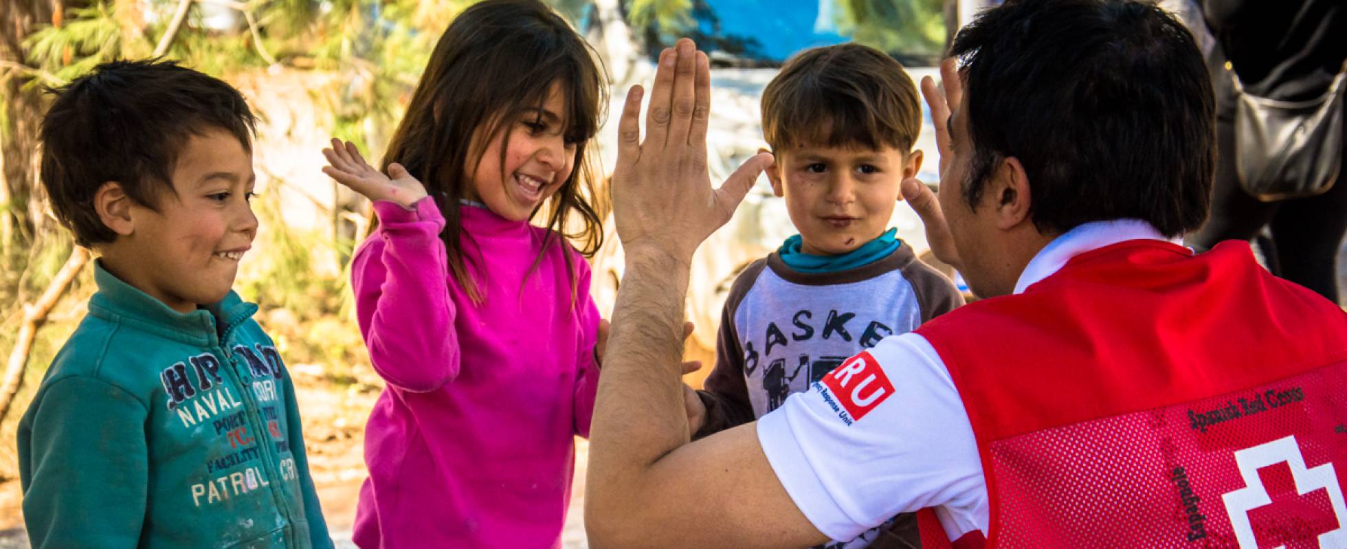 Un voluntario de la Cruz Roja juega con unos niños. Foto de Cruz Roja Española.