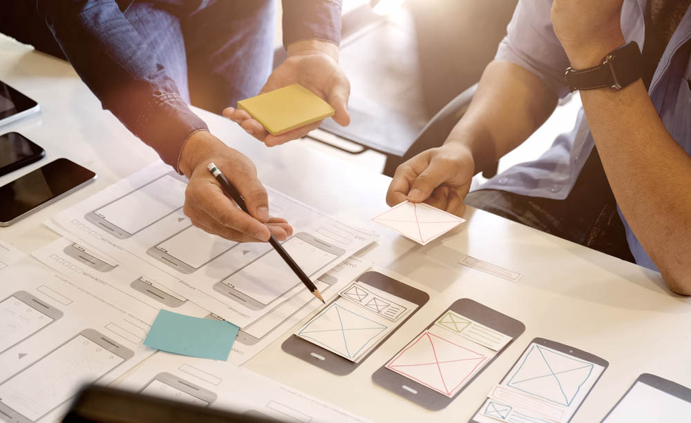 Varias persoas traballan no deseño dunha app para teléfono móbil.