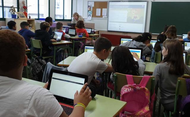 Alumnos en una clase usando una tablet.