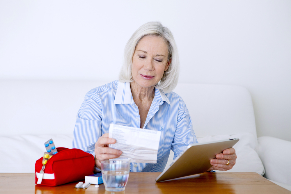 Una mujer mayor busca información en un ordenador sobre un medicamento.