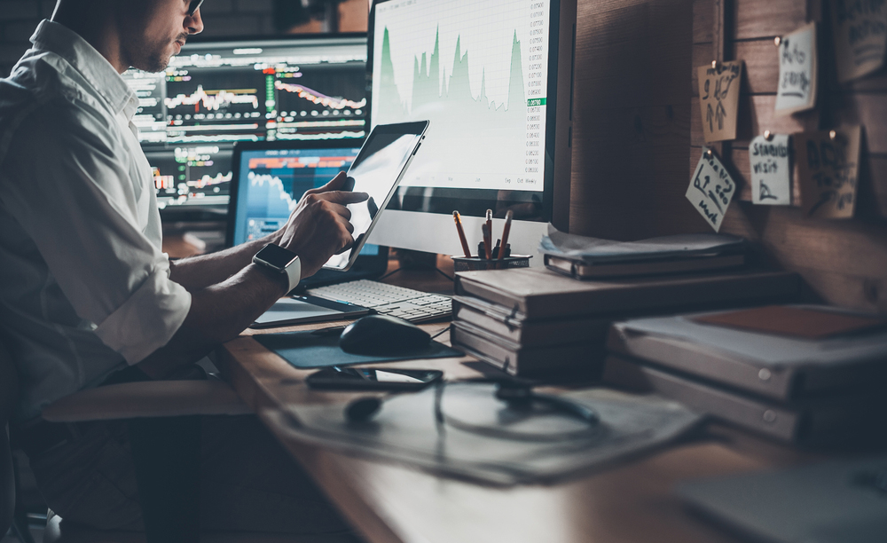 Un hombre en su puesto de trabajo rodeado de dispositivos tecnológicos.