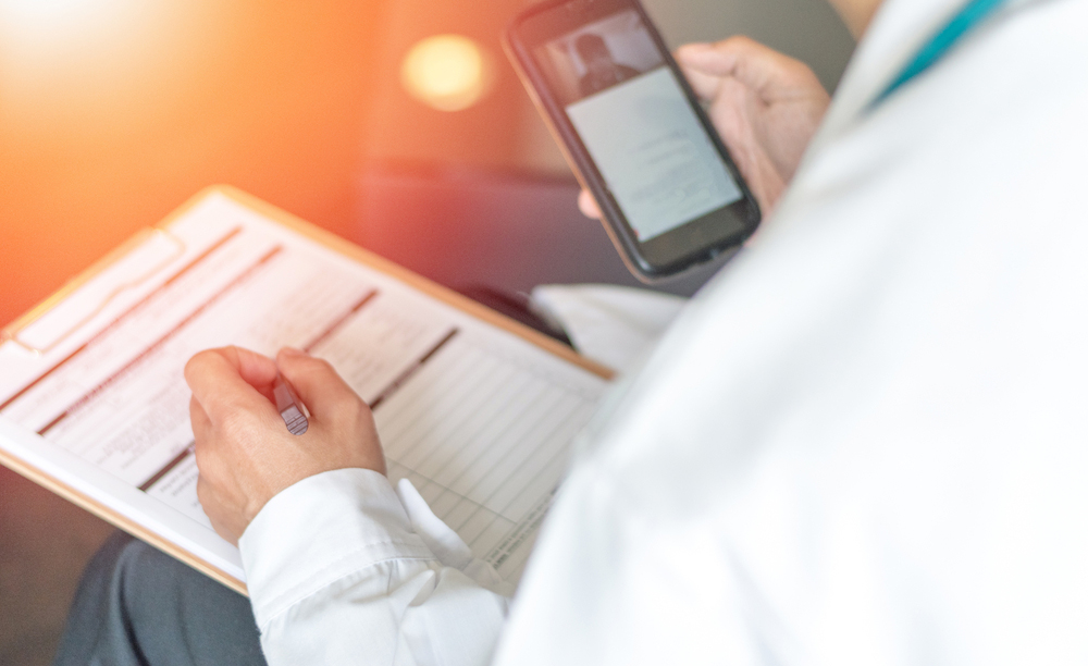 Un doutor utiliza o seu teléfono móbil para o seguimento dun paciente.