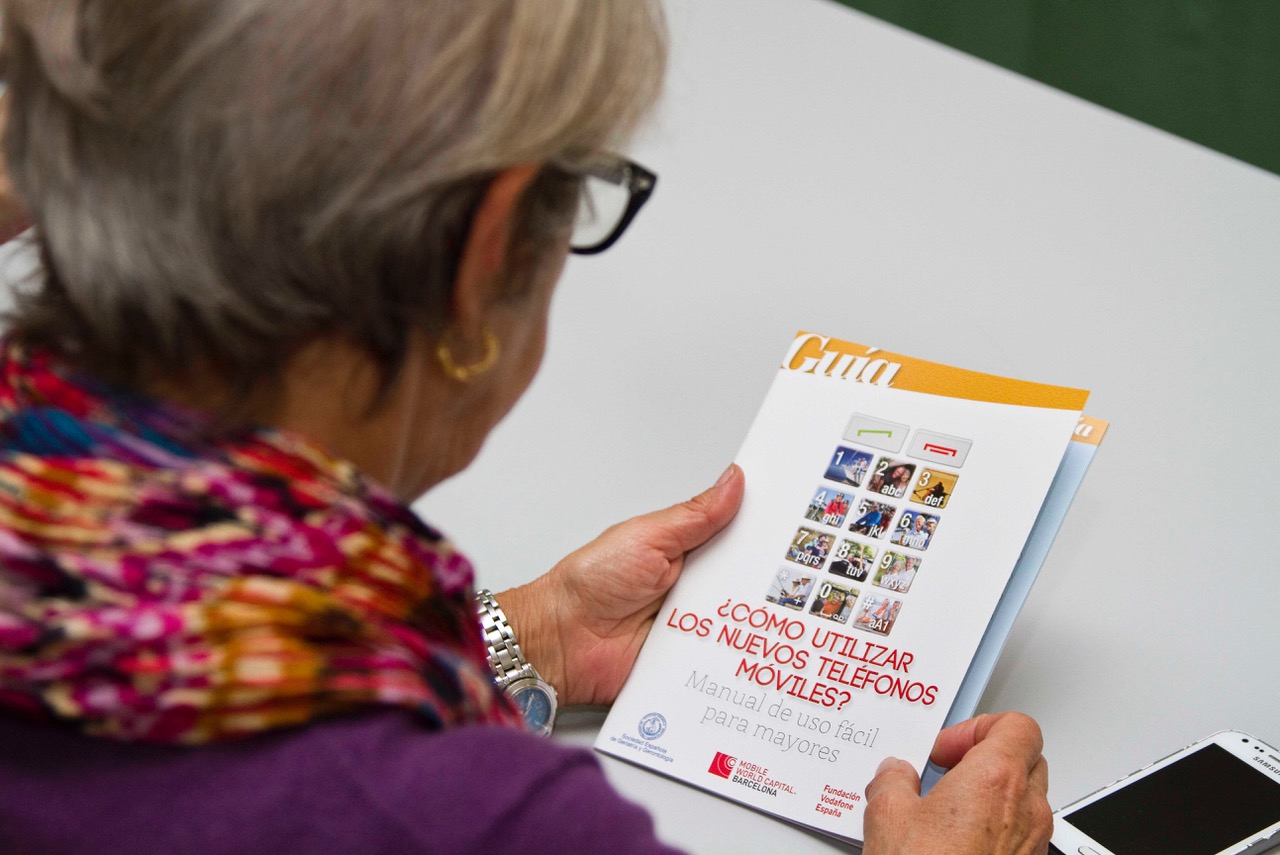 Señora mayor ojeando la guía de uso de smartphones.