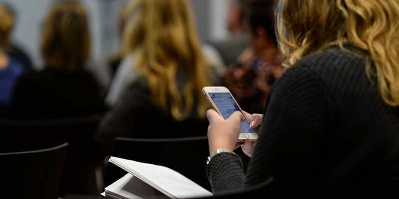 Mujer de espaldas usando un smartphone.
