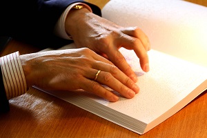 Manos leyendo libro en Braille.