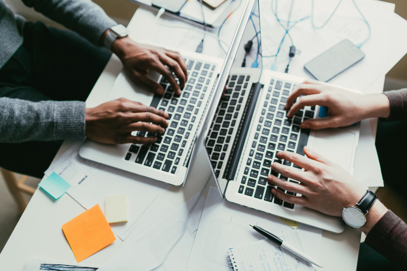 Dúas persoas traballando en dous portátiles.