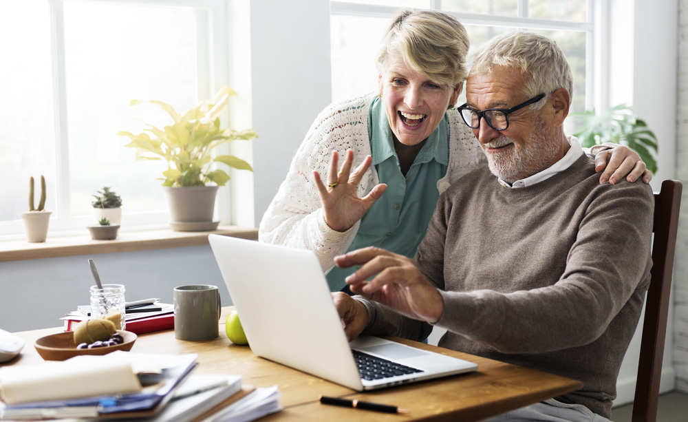 Unha parella de persoas maiores utiliza Internet cun computador portátil.