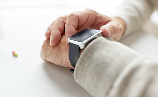 Unha persoa maior consulta o seu reloxo intelixente antes de tomar un medicamento.