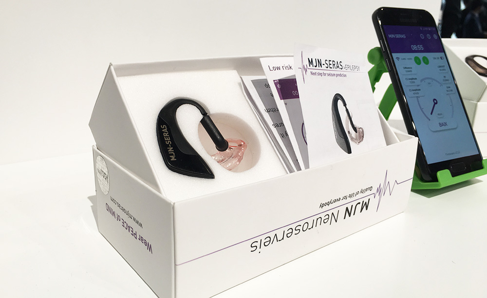 Imaxe dun dispositivo MJN-Seras dentro da súa caixa e xunto a un teléfono móbil.