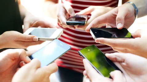 Manos de adolescentes con teléfonos móviles.