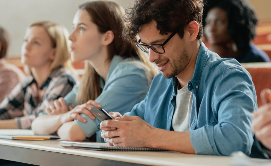 Un mozo utiliza o seu smartphone nunha clase na universidade.