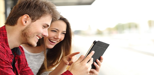 Dous mozos mirando riseiros un smartphone.