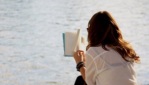 Mujer de espaldas leyendo un libro.