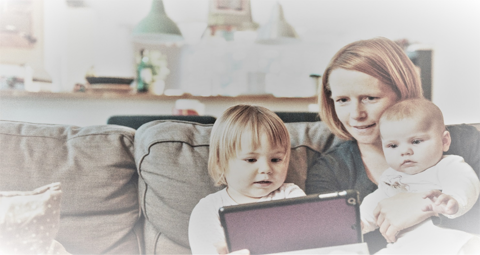 Unha muller con dous nenos pequenos nun sofá mirando unha tableta.