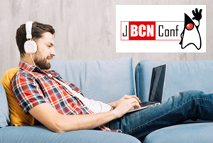 Joven con cascos tumbado en un sofá con un portátil encima de las piernas.