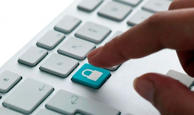 Mano a punto de pulsar un botón con la imagen de un candado en un teclado.