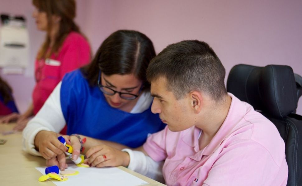 Cuidadora ayudando a joven con discapacidad.