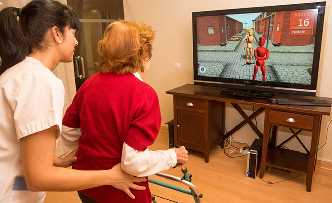 Unha muller maior utiliza a tecnoloxía de Rehametrics acompañada dunha enfermeira.