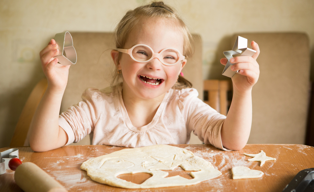 Una niña con síndrome de Down se divierte cocinando.