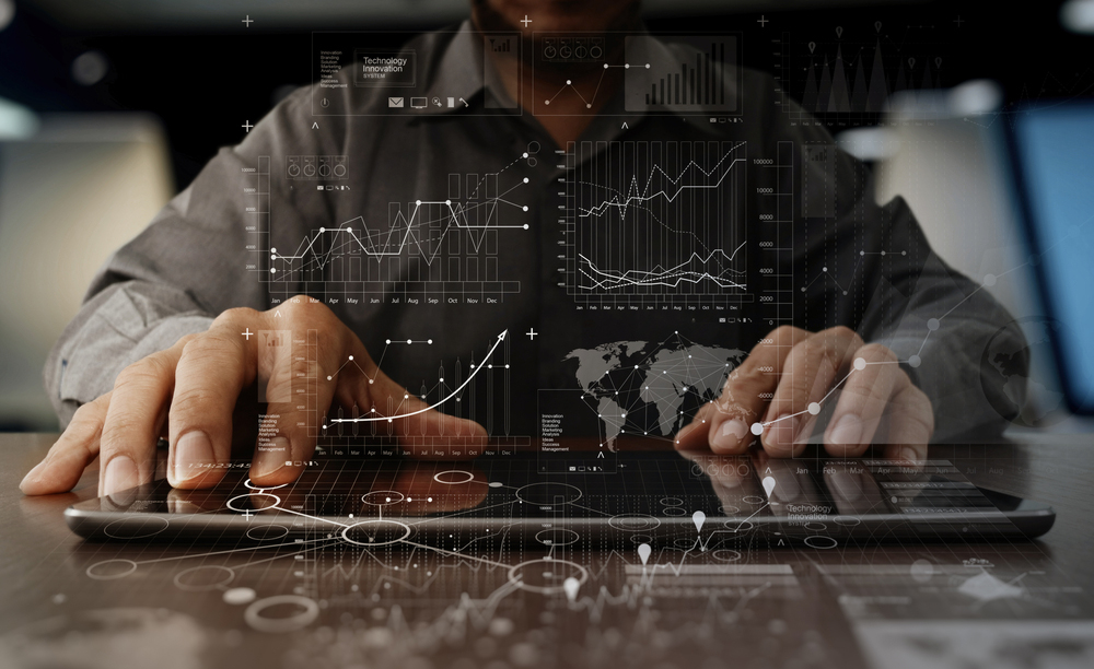 Un hombre maneja una tableta con infografía de tablas y gráficos por encima.