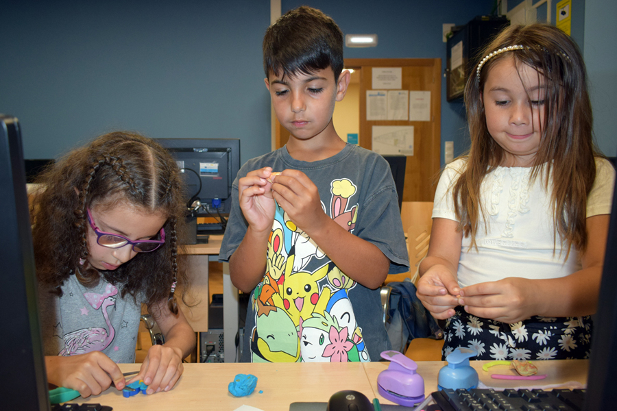 Dos niñas y un niño experimentando con tecnología.