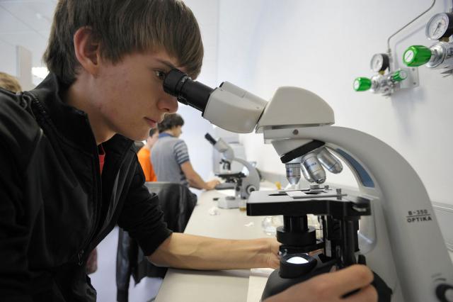 Un chico mirando a través de un microscopio.