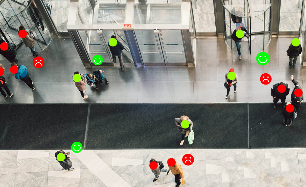 Fotografía da entrada a un edificio mostrando quen garda a distancia social e quen non.