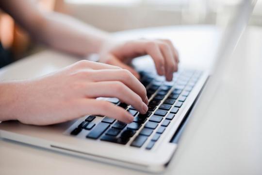 Manos de adolescente sobre el teclado de un portátil.