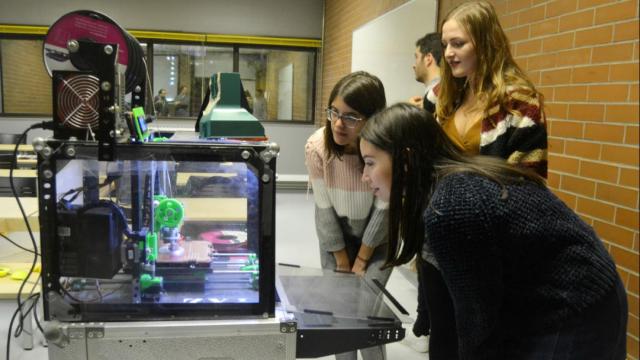 Tres jóvenes comprobando el funcionamiento de una impresora 3D.
