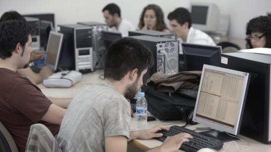 Alumnos universitarios usando ordenadores en un aula.