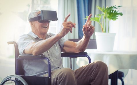 Anciano en silla de ruedas disfrutando de la realidad virtual.