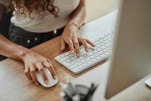 Manos de mujer usando un ratón y un teclado.