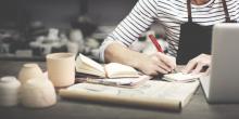 Persoa artersá tomando notas nunha libreta.