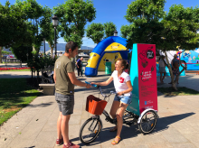 Mujer en triciclo repartiendo propaganda de la campaña.