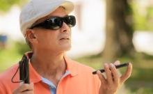Un hombre mayor con discapacidad visual utiliza un teléfono móvil.
