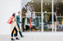 Dos jóvenes de compras pasan por delante de un escaparate.