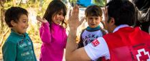 Un voluntario da Cruz Vermella xoga cuns nenos. Foto de Cruz Vermella Española.
