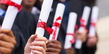 Manos sosteniendo títulos de graduación.