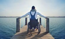 Una persona en silla de ruedas en un muelle de un lago.