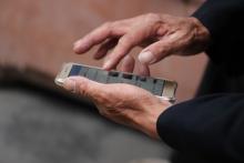 Manos de persona mayor sosteniendo un smartphone.